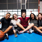 Group of teenagers sitting together on a basketball court