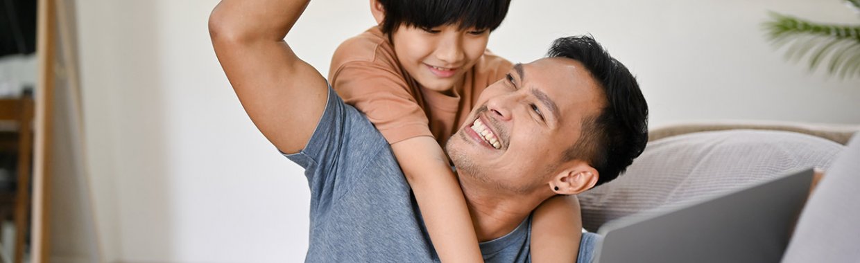 A child on parents shoulder, both smiling.