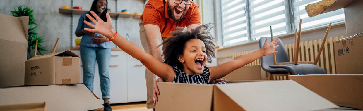 Husband and pregnant wife having fun with their daughter in their new home while unboxing packages