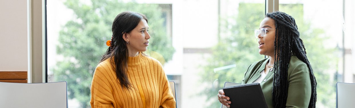 A serious young female therapy patient listens attentively to a caring female therapist