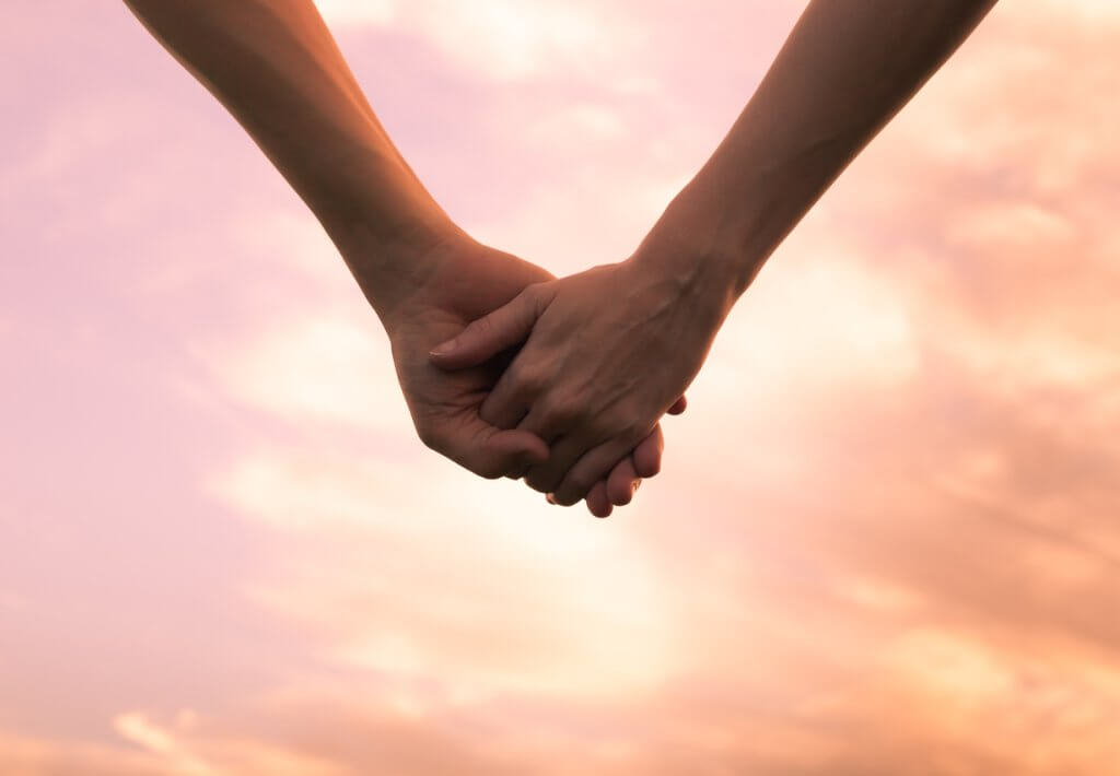 Couple holding hands against the sunset.